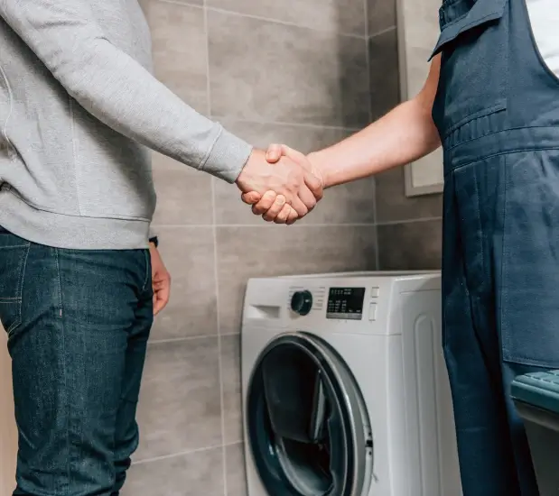 all fix appliance repair man and woman shake hands in front of a washing machine