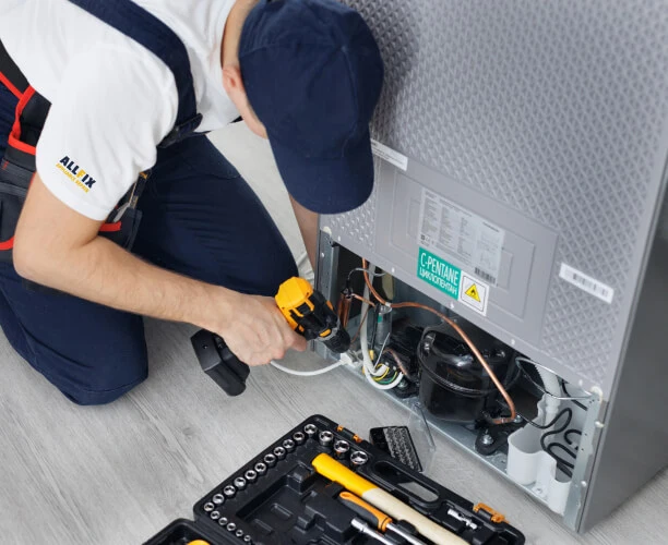 all fix appliance repair technician is engaged in repairing a refrigerator